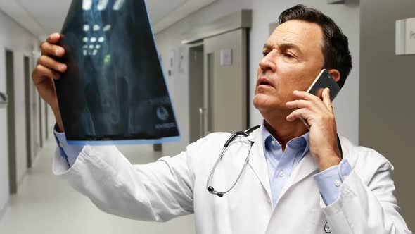 Male doctor talking on mobile phone while talking on mobile phone in corridor