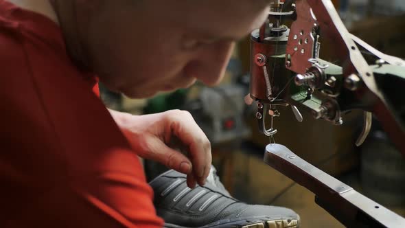 Male Shoemaker in Red Clothes Repairing Shoes By the Light of a Lamp