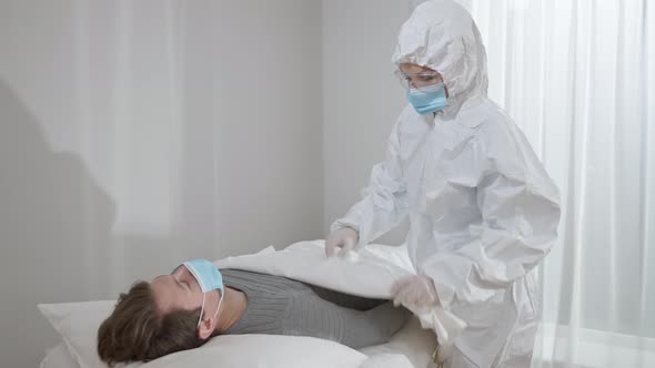 Professional Doctor or Nurse Taking Care of Ill Patient Lying on Medical Couch Coughing