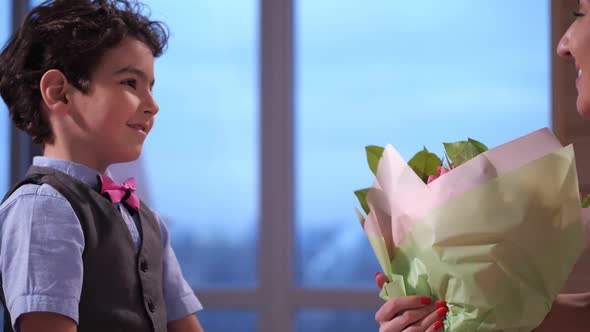 Close Up Adorable Son Presenting Flowers To Mom
