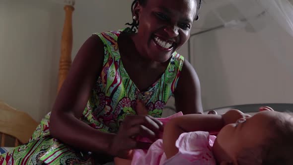 A close up of an African mother laughing and playing with her baby daughter.