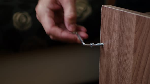 A Man's Hand Screws a Screw Into a Piece of Wood. Man's Work