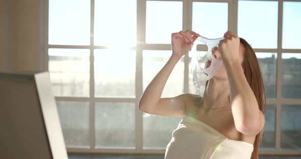 Young Woman Applying Cosmetic Mask on Face