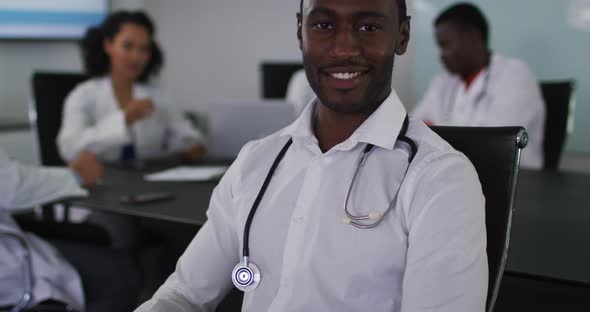 Portrait of african american male doctor sitting in meeting room looking to camera smiling