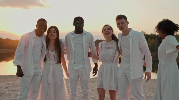 Group of Friends Hugging at the Beach Party Looking at the Camera