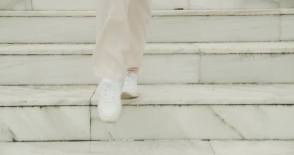 Woman In Sneakers Walking Down Marble Steps