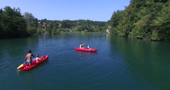 Four young friends paddling canoe and splashing each other with water