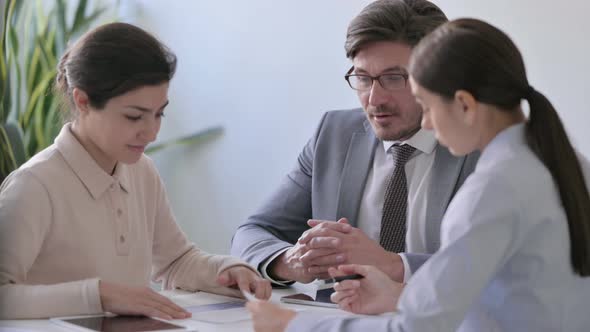 Serious Male and Female Business People having Discussion with Papers