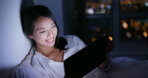 Woman use of mobile phone and lying on bed at night