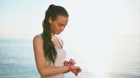 Young Woman Using Smart Watches in Front of the Sea During Sunset