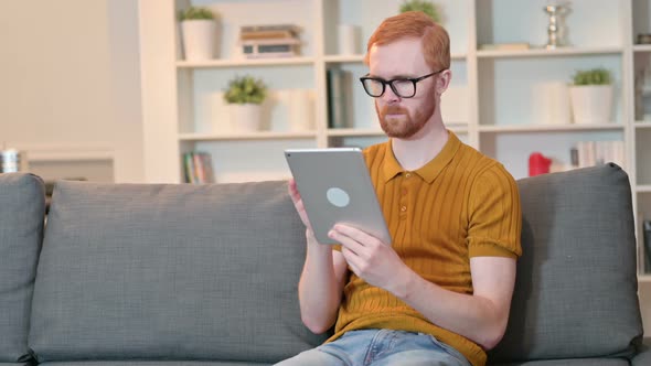 Serious Redhead Man Using Tablet at Home 