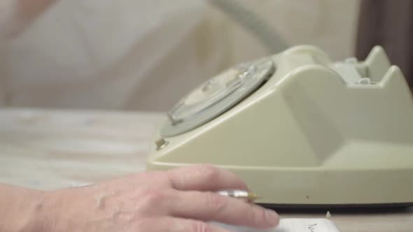 Dialing on a retro vintage phone with woman taking notes