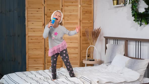 Little Girl Singing with a Toy Microphone at Home