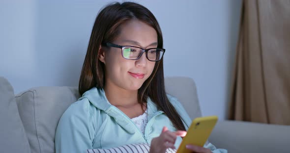 Woman drink of water and use of mobile phone at night inside living room