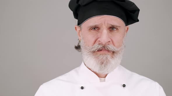 Portrait of Senior Chef Showing Emotions on Gray Background