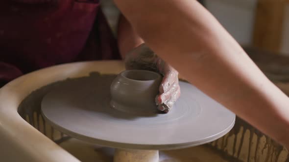 Close up view of female potter creating pottery on potters wheel at pottery studio