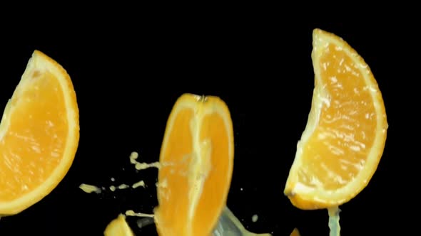 Slices of Orange are Bouncing with the Splashes of Juice on the Black Background