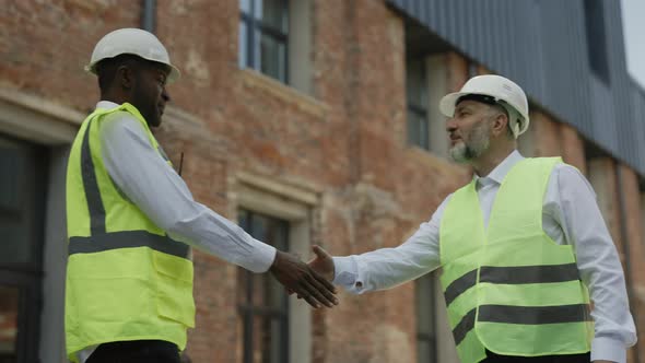 Men Greeting Each Other with Hand Shaking at Building Site