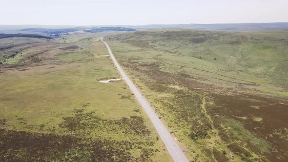 Countryside road cutting through the Dartmoor landscape, aerial slowing