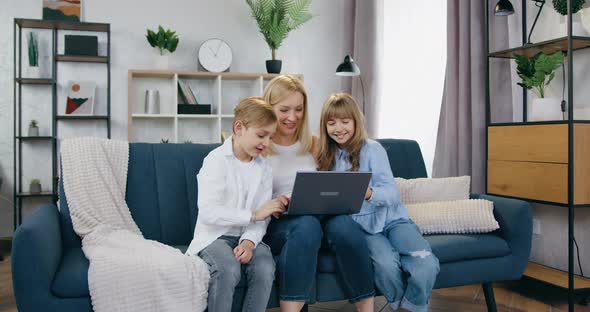 Mother and Her Positive Son and Daughter Sitting Together on the Couch During videochat