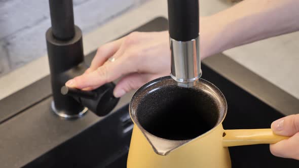 Filling up cooking coffee pot with water for making a morning coffee