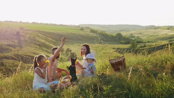 Friendly Family on a Picnic with a Dog in Nature