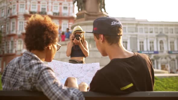 Girl Taking Pictures of Her Friends Looking at Map Sitting on Bench Slow Motion