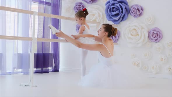 Ballet Teacher Is Teaching Little Girl To Stretch Legs Near the Barre Stand