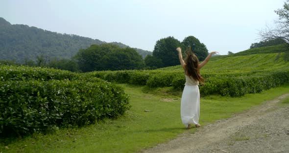 Young Happy Woman Is Running Outdoors in Garden on Slope of Mount, Whirling Around Herself