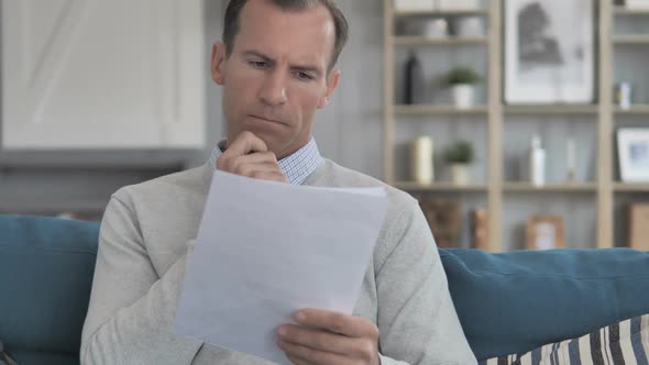 Pensive Middle Aged Man Thinking While Reading Contract