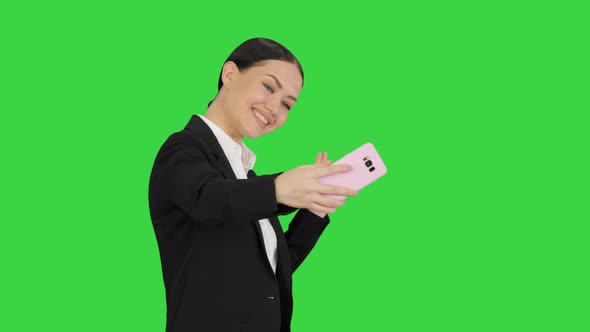 Smiling Businesswoman Taking Selfie on Her Phone While Walking on a Green Screen, Chroma Key