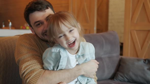 Portrait of Happy Father and Little Daughter Hugging and Laughing Having Fun at Home