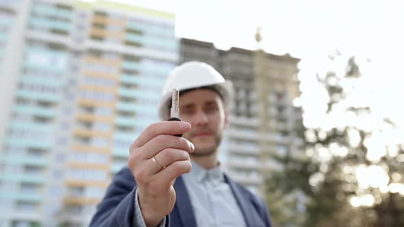 The builder shows the key of the apartment in front of the camera