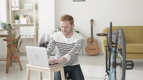 Young Man Repairing His Bicycle Wheel Looking a Tutorial on Internet