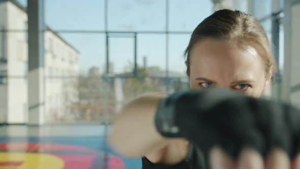 Professional Female Boxer Making Punch Moves with Wrapped Hands Training in Gym