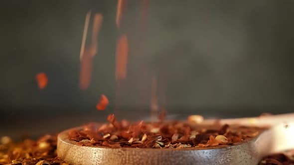 Flakes of Red Hot Chili Pepper in Wooden Spoon Closeup on a Kitchen Table.