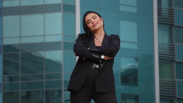 Young Successful Elegant Hispanic Businesswoman in Business Suit Stands in Confident Pose with Arms
