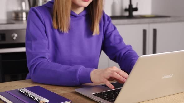 Young Adult Woman in Violet Hoodie Type on Laptop