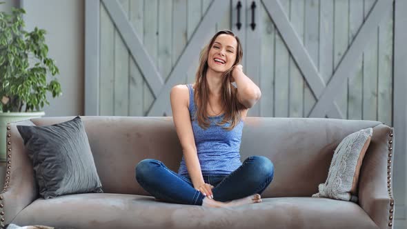 Adorable Playful Girl Sitting on Couch Laughing Relaxing at Home