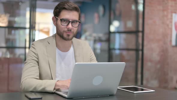 Young Man with Laptop Smiling at Camera