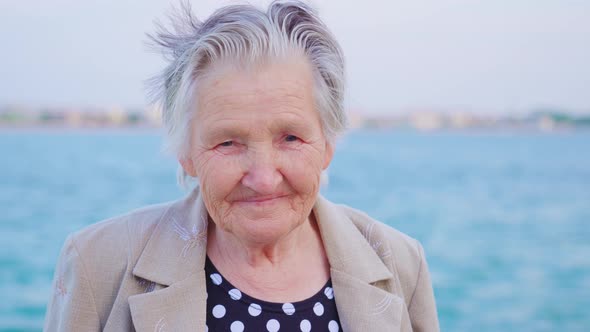 Senior Lady Traveler Looks Into Camera Standing on Promenade