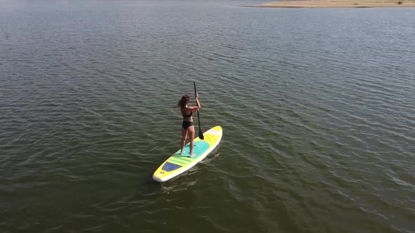 Caucasian Woman Riding a SUP Board on the Lake