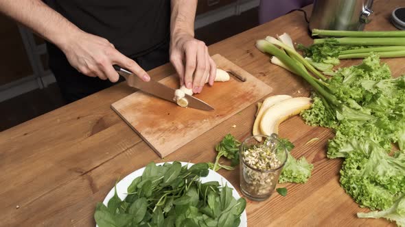 Making Green Juice at Home Male Hands Cut Banana with a Knife on a Board Table in the Kitchen