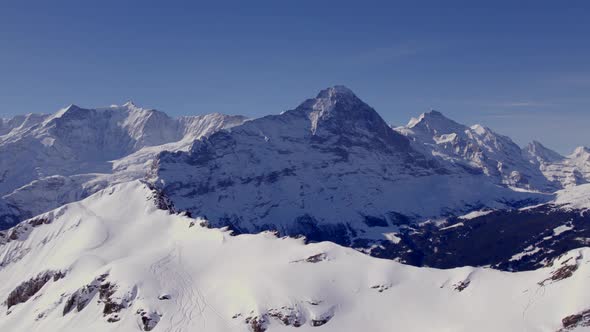 aerial drone footage flying over a snowy mountain top towards Eiger North Face