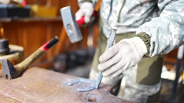 Professional Blacksmith Hand Holding Hammer Working with Horseshoe at Outdoor Workshop Close Up View