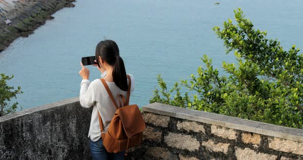 Woman go hiking and taking photo of the sea view