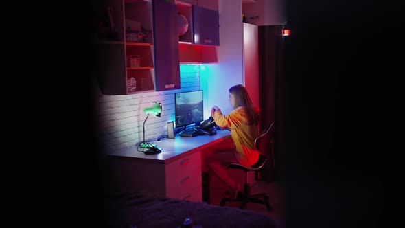 Woman playing on computer. Girl sits in the simulator of a car and playing the game