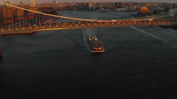 Large Cargo Boat Passing Under Busy Manhattan Bridge in Sunset Time