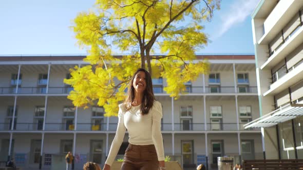 Slow motion shot of smiling woman jumping in front of a tree in autumn