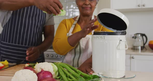 African american senior couple putting chopped vegetables in a tiffin box in the kitchen at home